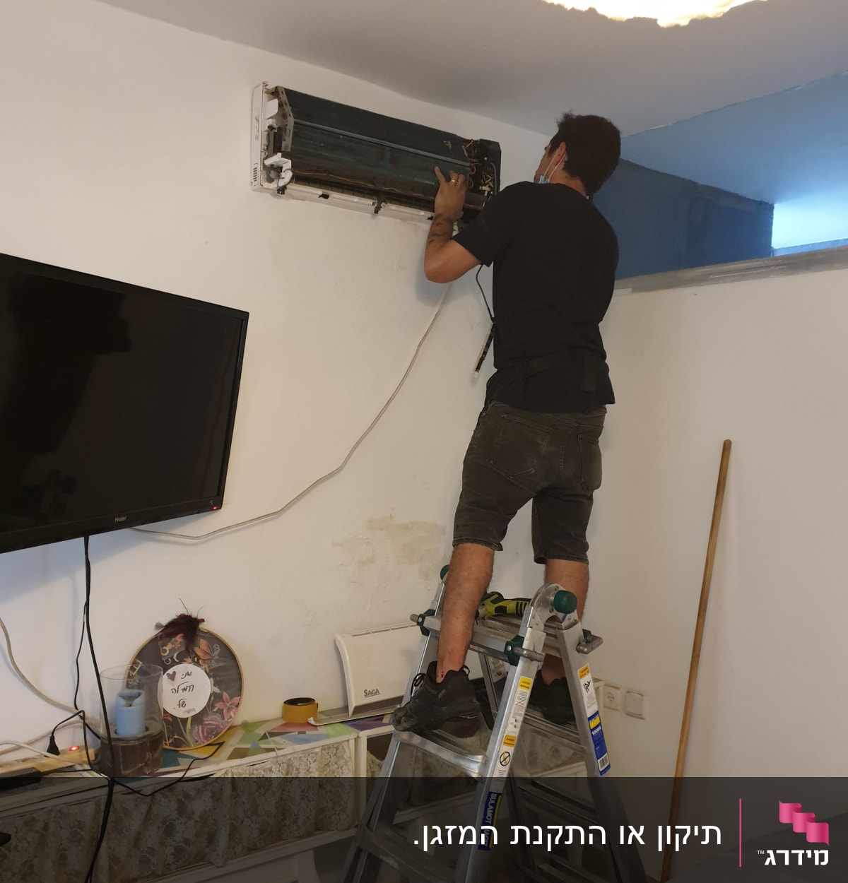 אדם מתקן מזגן על סולם בחדר